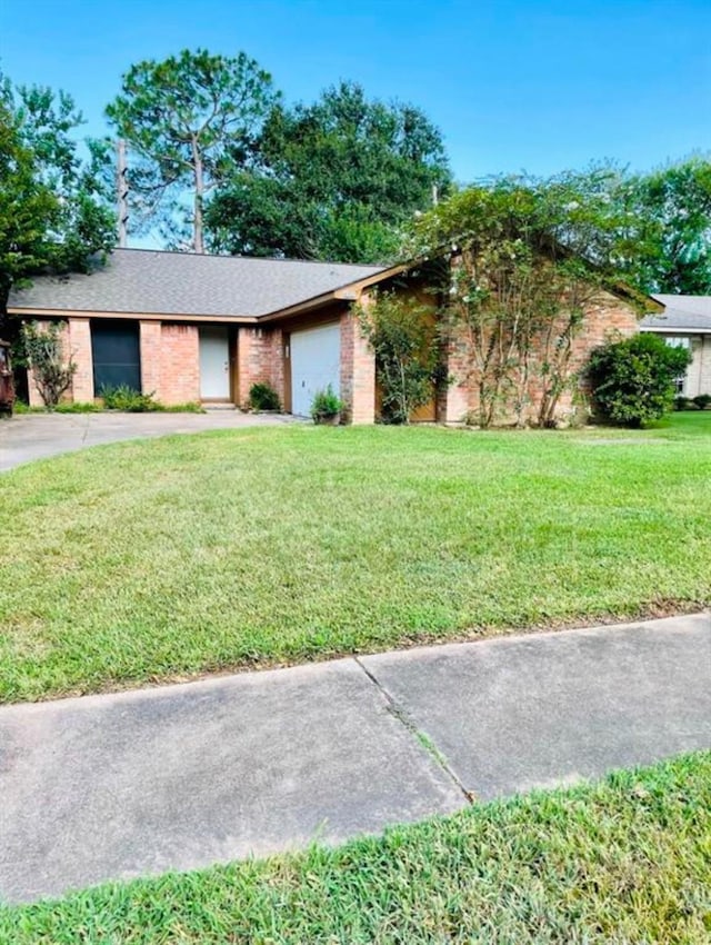 view of front facade with concrete driveway, a front lawn, an attached garage, and brick siding