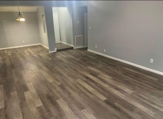 unfurnished living room featuring dark wood-style floors, visible vents, and baseboards