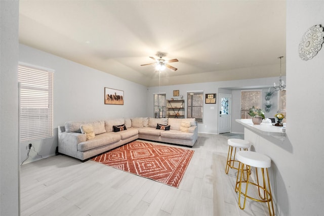 living room with ceiling fan with notable chandelier and light wood-type flooring