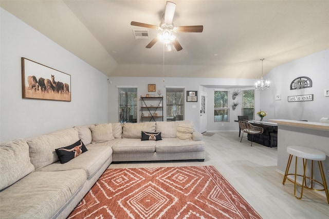 living room featuring vaulted ceiling, ceiling fan with notable chandelier, and light hardwood / wood-style floors