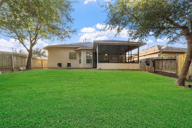 rear view of property featuring a sunroom and a lawn