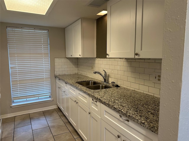 kitchen with white cabinetry, sink, backsplash, and stone countertops