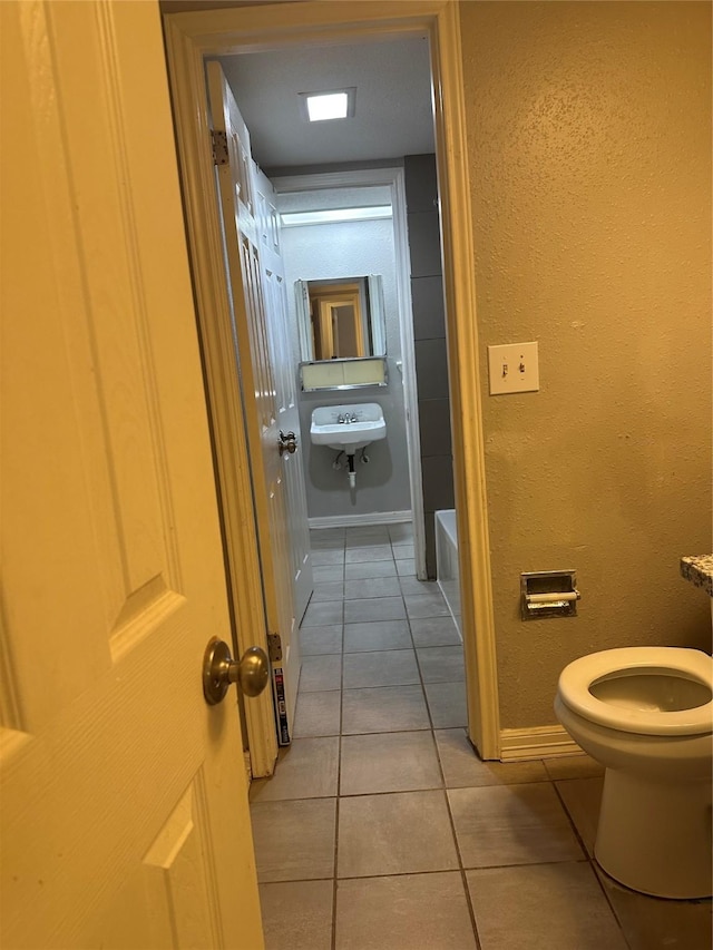 bathroom featuring sink, tile patterned floors, a tub, and toilet