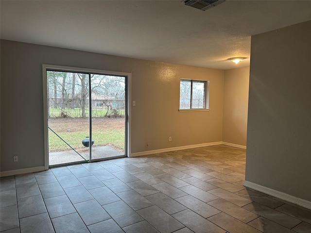 tiled empty room featuring a textured ceiling