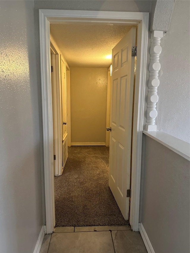 hall with tile patterned flooring and a textured ceiling