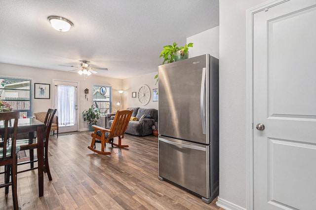 kitchen featuring hardwood / wood-style floors, stainless steel fridge, a textured ceiling, and ceiling fan