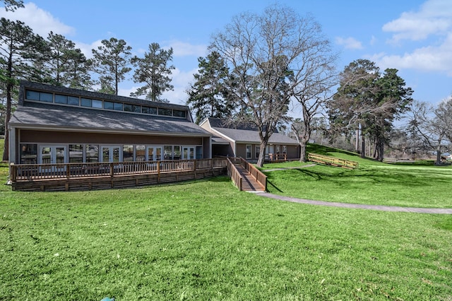 back of house featuring french doors, a deck, and a lawn