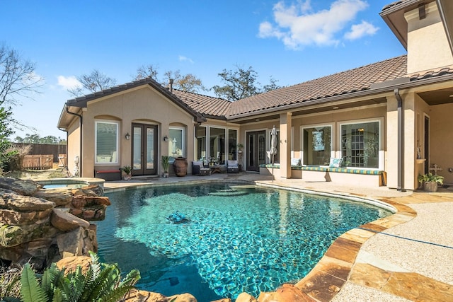 view of swimming pool featuring a pool with connected hot tub, french doors, a patio area, and fence