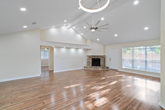 unfurnished living room with a fireplace, beam ceiling, light hardwood / wood-style flooring, and ceiling fan