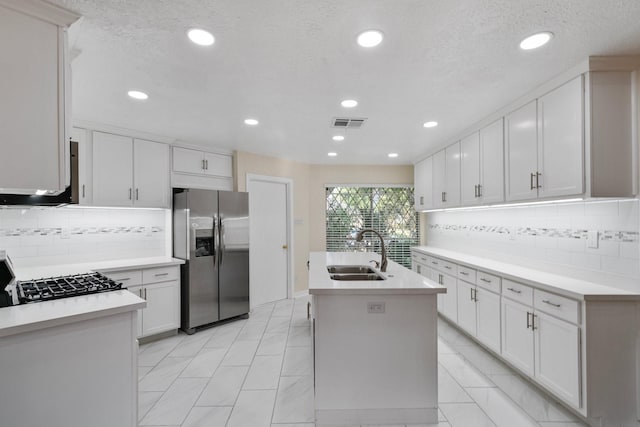 kitchen with sink, white cabinetry, stove, stainless steel refrigerator with ice dispenser, and an island with sink