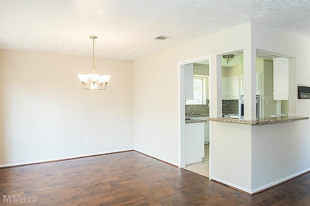 interior space with a notable chandelier, a textured ceiling, and light wood-type flooring