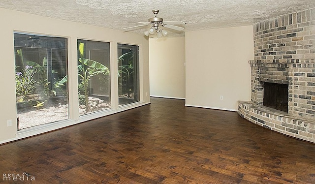 unfurnished living room featuring a brick fireplace, dark wood-type flooring, a textured ceiling, and ceiling fan