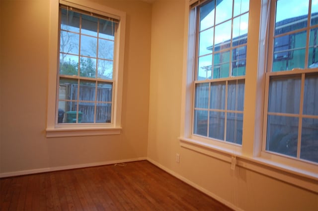 unfurnished room featuring plenty of natural light and dark hardwood / wood-style flooring