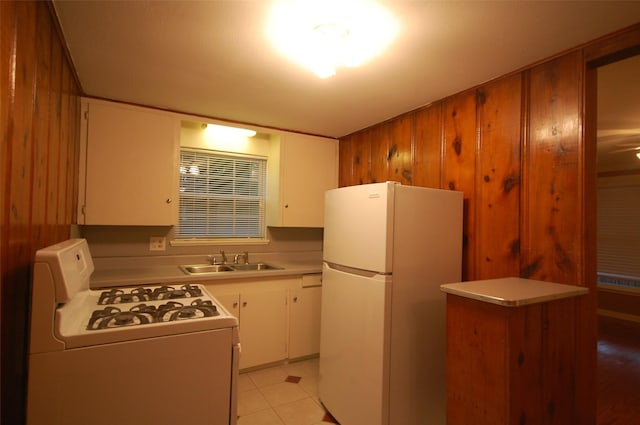 kitchen featuring sink, wooden walls, white cabinets, and white appliances