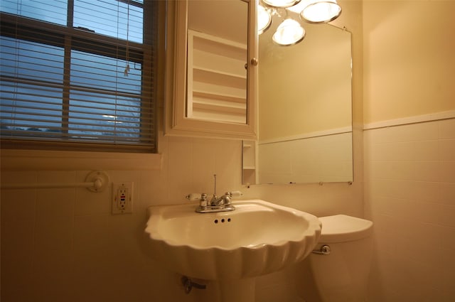 bathroom featuring toilet, sink, and tile walls