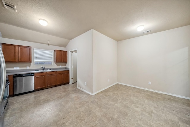 kitchen featuring vaulted ceiling, stainless steel dishwasher, sink, and a textured ceiling