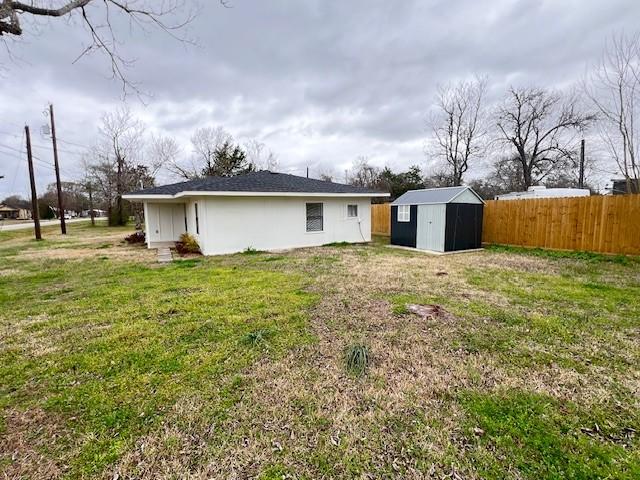 rear view of property with a storage shed and a lawn