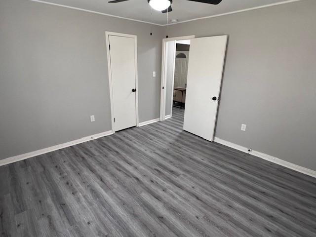 unfurnished bedroom with ornamental molding, ceiling fan, and dark hardwood / wood-style flooring