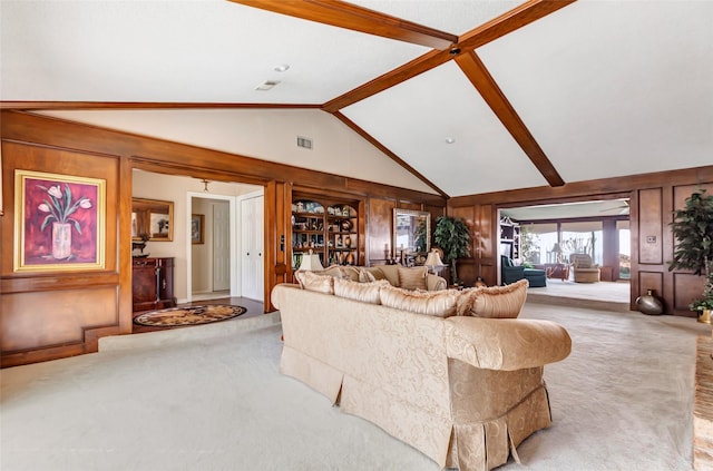 carpeted living room with high vaulted ceiling, beamed ceiling, and wood walls