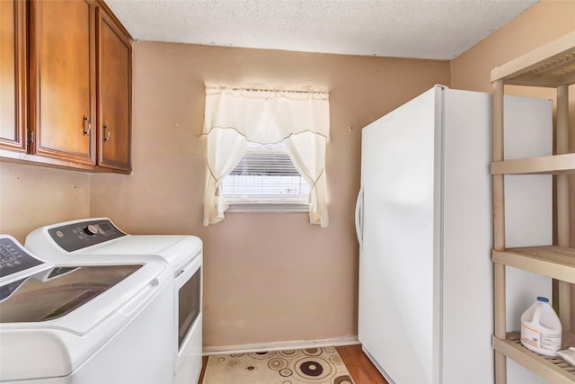 laundry room with washing machine and dryer, cabinets, and a textured ceiling