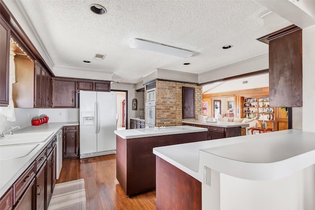 kitchen featuring sink, white appliances, a center island, wood-type flooring, and kitchen peninsula