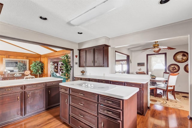 kitchen featuring dark brown cabinetry, a center island, light hardwood / wood-style floors, and kitchen peninsula