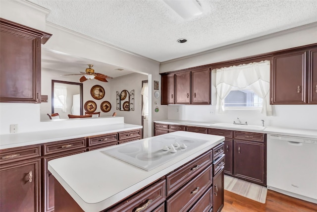 kitchen featuring sink, white appliances, a center island, light hardwood / wood-style floors, and a textured ceiling