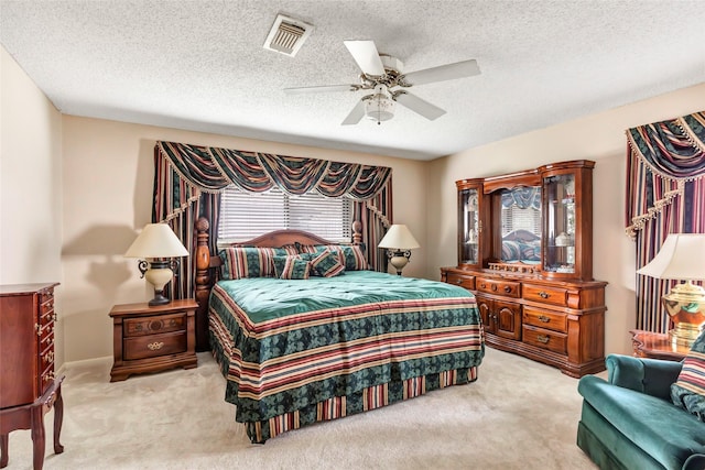 bedroom featuring light carpet, a textured ceiling, and ceiling fan