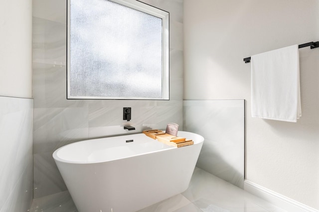 bathroom featuring a bathing tub, plenty of natural light, and tile walls