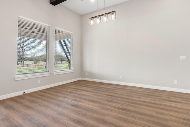 unfurnished room with dark wood-type flooring and beam ceiling