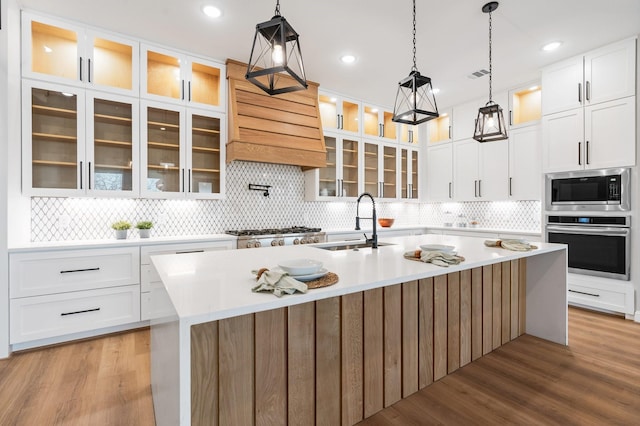 kitchen featuring a kitchen island with sink, white cabinets, and appliances with stainless steel finishes