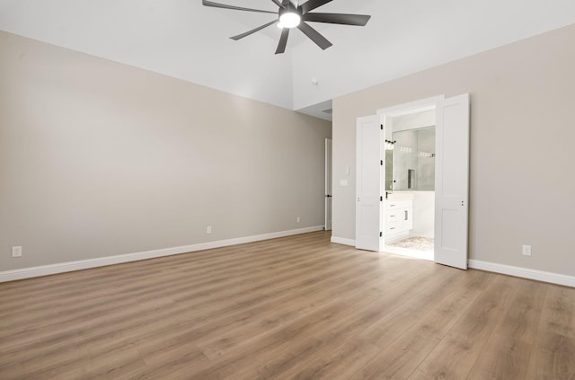 unfurnished bedroom featuring ensuite bath, light hardwood / wood-style flooring, ceiling fan, and vaulted ceiling