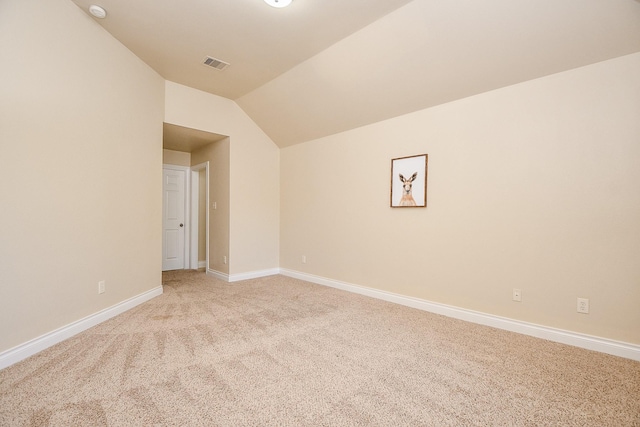 carpeted spare room featuring vaulted ceiling