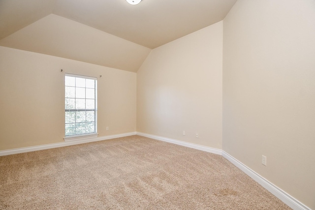 carpeted empty room featuring lofted ceiling