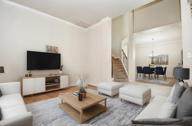 living room featuring an inviting chandelier, crown molding, and light hardwood / wood-style floors