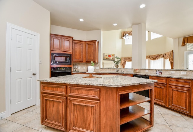 kitchen with light stone counters, light tile patterned floors, a kitchen island, and black appliances