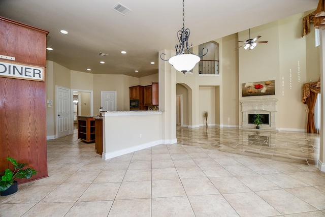 kitchen featuring pendant lighting, ceiling fan, black microwave, a high end fireplace, and kitchen peninsula