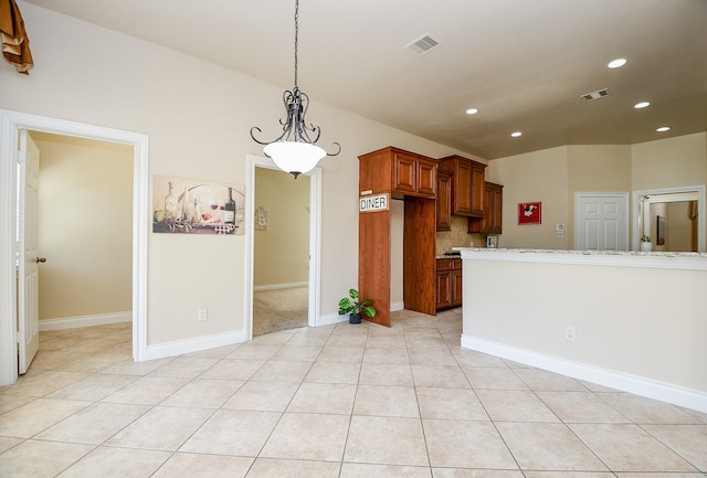 kitchen with built in refrigerator, light tile patterned floors, backsplash, and decorative light fixtures