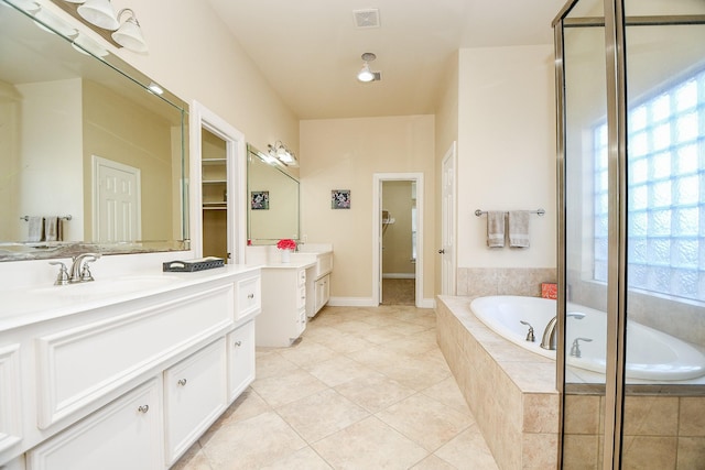 bathroom featuring tile patterned floors, tiled bath, and vanity