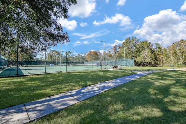 view of tennis court featuring a yard