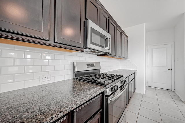 kitchen featuring stainless steel appliances, dark brown cabinets, decorative backsplash, and dark stone counters