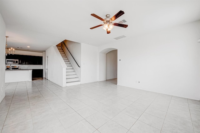 unfurnished living room featuring sink, ceiling fan with notable chandelier, and light tile patterned flooring