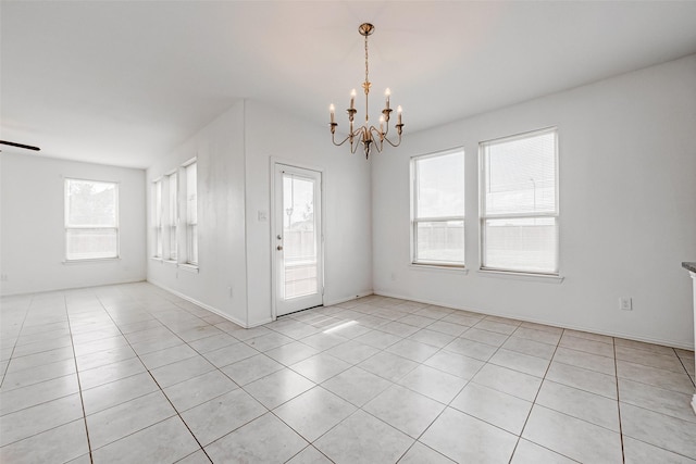 tiled spare room with a chandelier