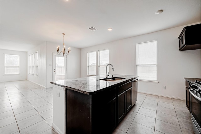 kitchen with sink, light tile patterned floors, an inviting chandelier, stainless steel appliances, and a center island with sink