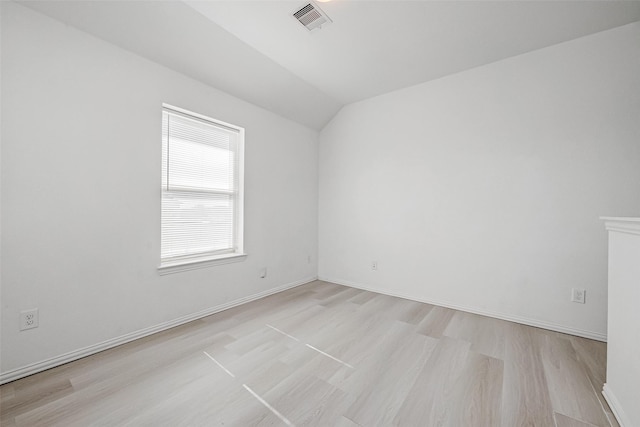 spare room with light hardwood / wood-style floors and vaulted ceiling