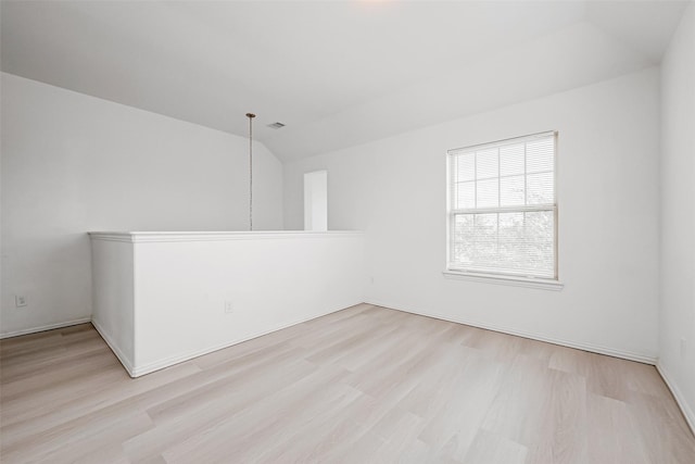 spare room with vaulted ceiling and light hardwood / wood-style flooring