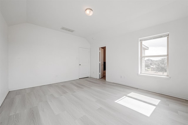 empty room featuring vaulted ceiling and light hardwood / wood-style floors