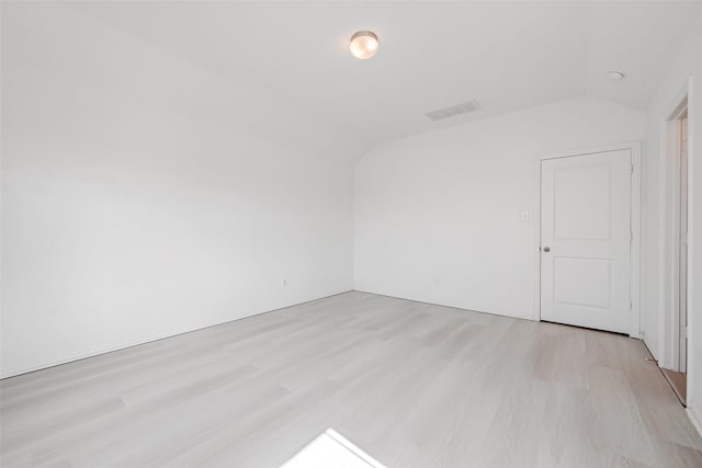 spare room featuring vaulted ceiling and light hardwood / wood-style floors