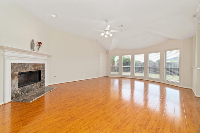 unfurnished living room with ceiling fan, lofted ceiling, a tiled fireplace, and light hardwood / wood-style flooring