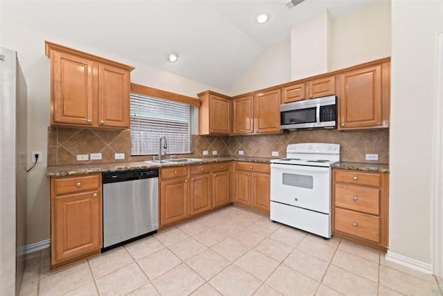 kitchen featuring lofted ceiling, sink, stone counters, appliances with stainless steel finishes, and light tile patterned flooring